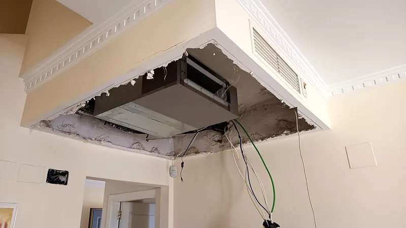 Unidad interior de conductos encajada en el falso techo de un salón, con la rejilla de retorno montada